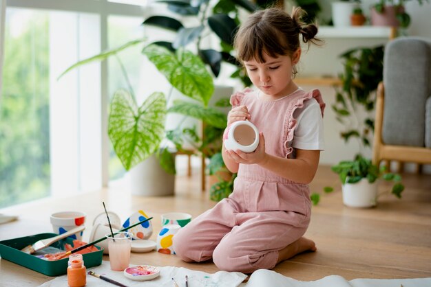 Niño pintando una maceta en casa