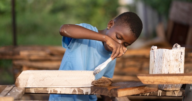 Niño pintando madera de tiro medio