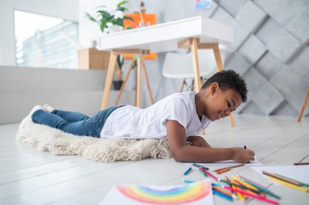 niño, pintura, acostado, en, alfombra, en, piso