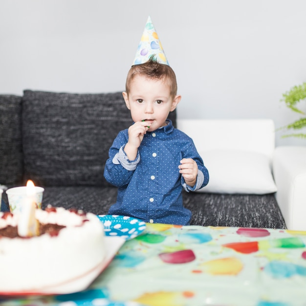 Niño con piruleta cerca de pastel