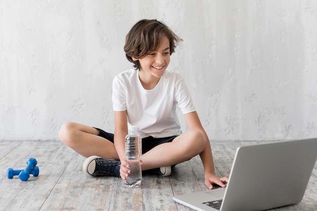 Niño en el piso al lado de la computadora portátil