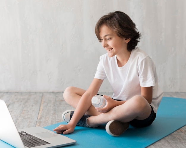 Niño en el piso al lado de la computadora portátil