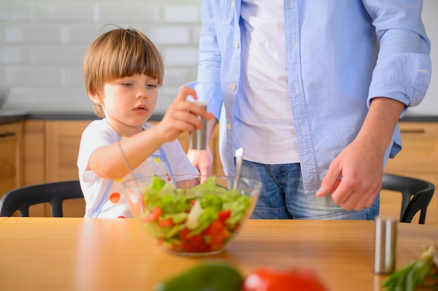 El niño pone sal en la ensalada