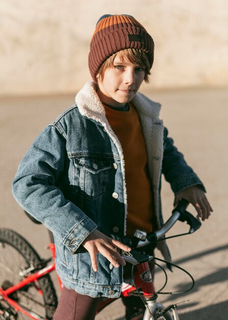 Niño posando al aire libre en la ciudad con su bicicleta