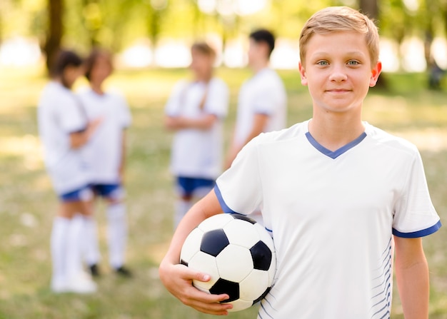 Niño posando con una pelota de fútbol al aire libre