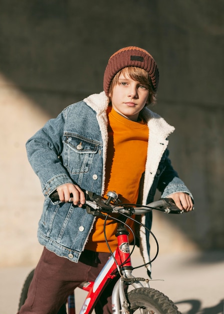 Niño posando con su bicicleta al aire libre en la ciudad