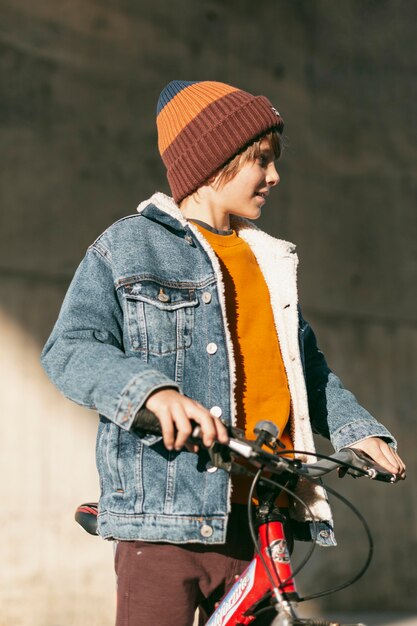 Niño posando con su bicicleta al aire libre en la ciudad