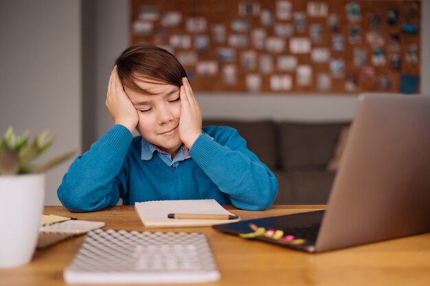 Un niño preadolescente harto de las clases en línea