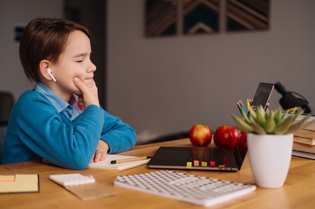 Un niño preadolescente usa una computadora portátil para hacer clases en línea