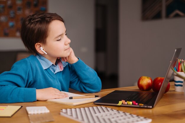 Un niño preadolescente usa una computadora portátil para hacer clases en línea