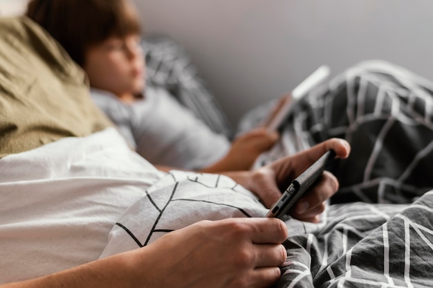 Niño de primer plano en la cama con dispositivo