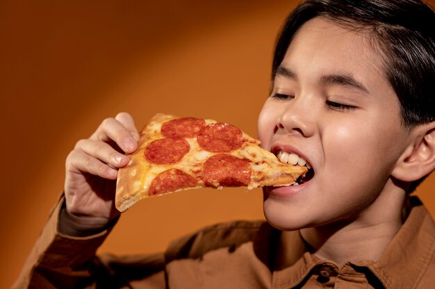 Niño de primer plano comiendo pizza