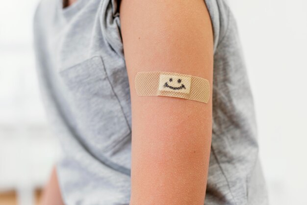 Niño de primer plano con parche sonriente en el brazo