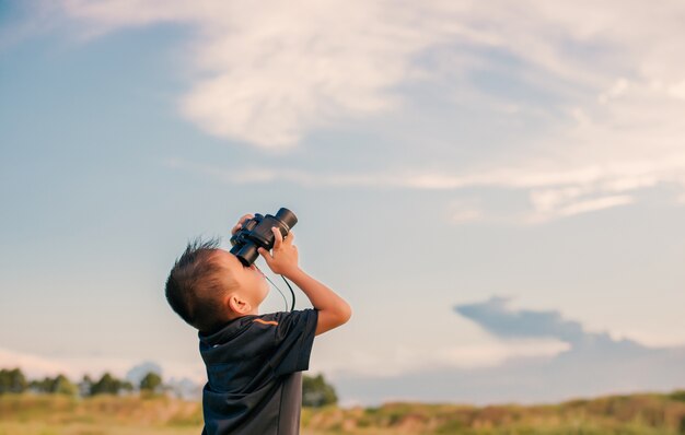 Niño con prismáticos mirando al cielo