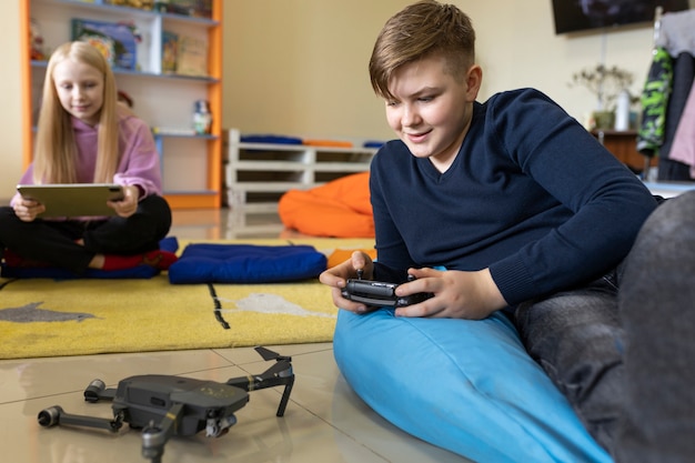 Niño probando un dron mientras una niña trabaja usando una tableta