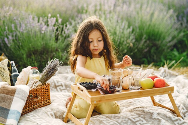 Niño provenzal relajante en campo de lavanda. Niña en un picnic.