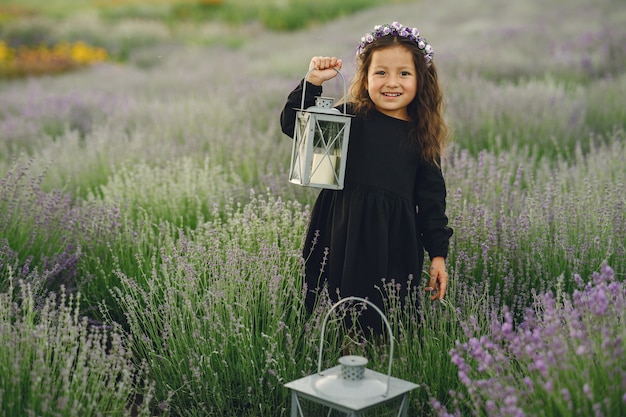 Niño provenzal relajante en campo de lavanda. Pequeña dama con un vestido negro. Chica con bolso.