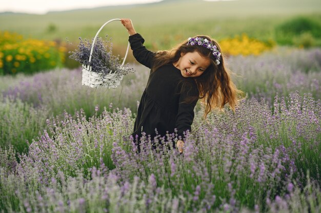 Niño provenzal relajante en campo de lavanda. Pequeña dama con un vestido negro. Chica con bolso.