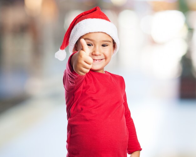 Niño con el pulgar arriba y el sombrero de papa noel