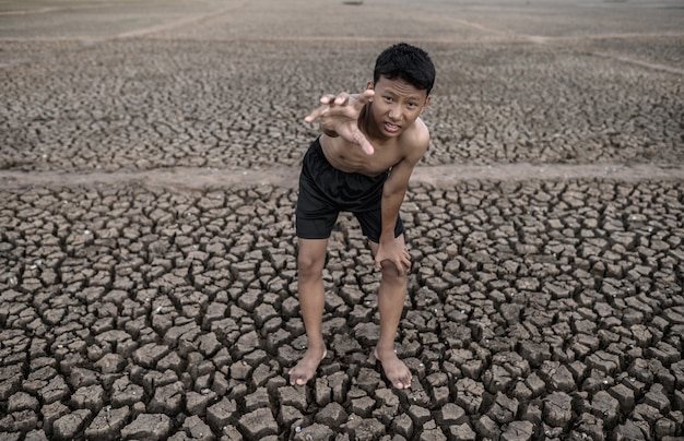 Foto gratuita el niño se puso de rodillas e hizo una marca para pedir lluvia, calentamiento global y crisis de agua.