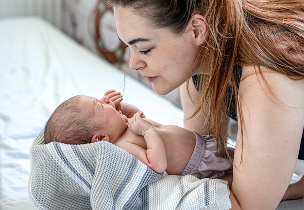 Foto gratuita el niño recién nacido llora en los brazos de la madre en el dormitorio.