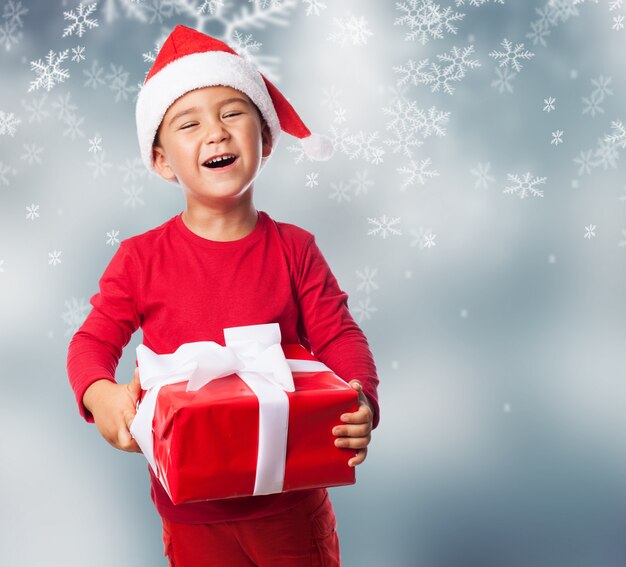 Niño con un regalo en un fondo de nieve