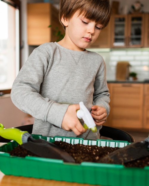 Niño regando cultivos en casa