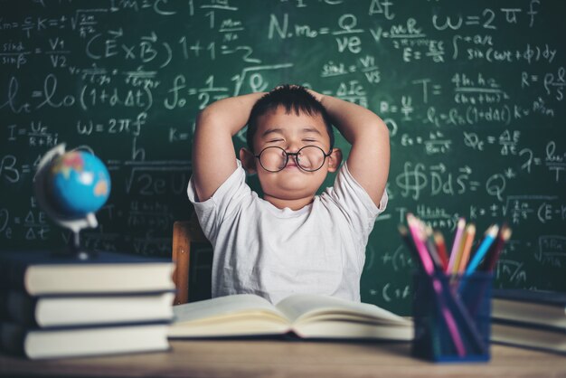 niño relajarse sentado a la mesa en el aula