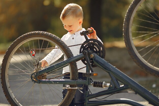 Niño repara su bicicleta en un parque