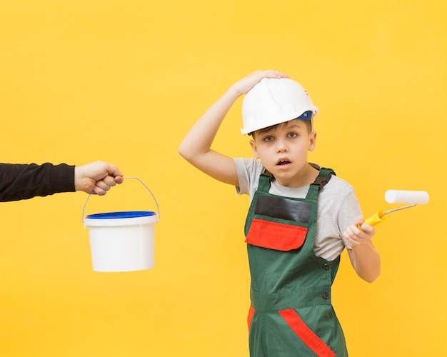 Foto gratuita niño reparador sorprendido con rodillo de pintura