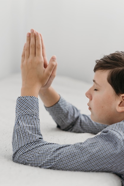 Niño rezando con las manos en los malos