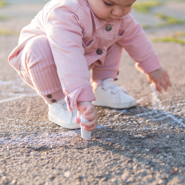 Niño en ropa rosa jugando con tiza