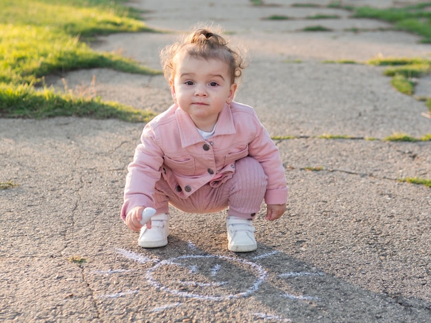 Niño en ropa rosa con tiza en la mano