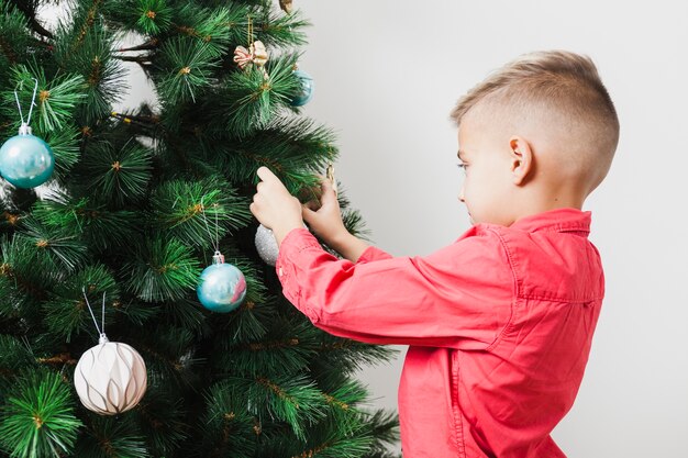 Niño rubio decorando árbol de navidad