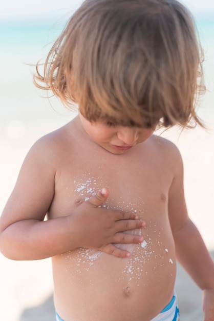 Niño rubio en la playa tiro medio