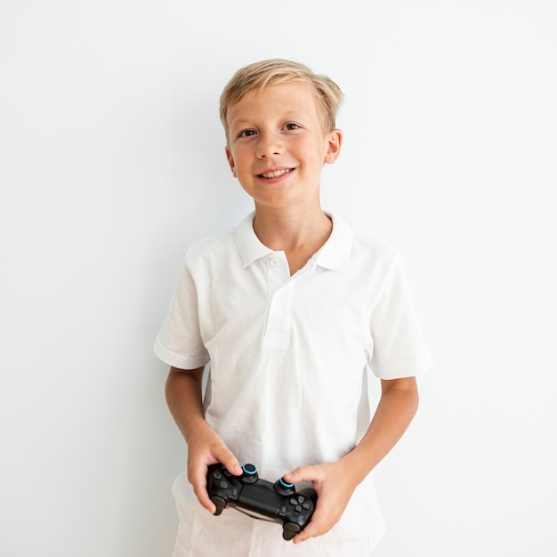 Foto gratuita niño rubio sonriente de tiro medio que sostiene un controlador