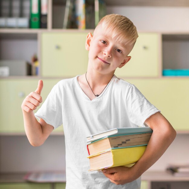 Niño rubio sosteniendo un montón de libros