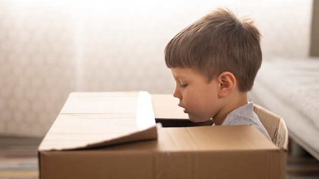 Foto gratuita niño sentado en caja de dibujos animados