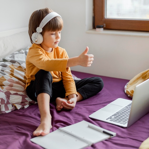 Foto gratuita niño sentado en la cama y aprendiendo thumbs up