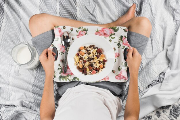 Niño sentado en la cama listo para tomar su desayuno en la mañana