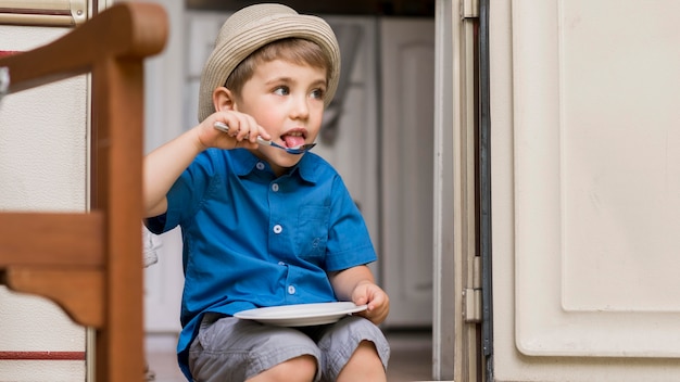 Niño sentado en una caravana mientras come