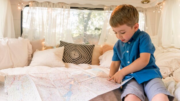 Niño sentado en una caravana y mirando en un mapa