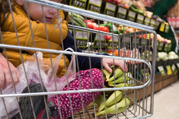 Niño sentado en el carrito de compras en la tienda