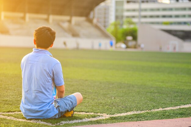 Niño sentado en el córner del campo de fútbol