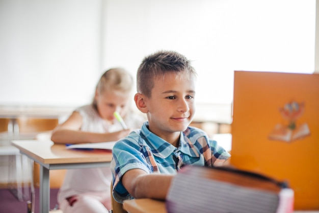 Niño, sentado, escuela, escritorio, lectura, libro de texto