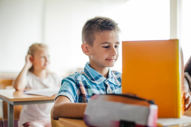 Niño, sentado, escuela, escritorio, lectura, libro de texto