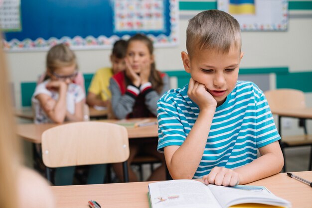 Niño, sentado, escuela, escritorio, lectura