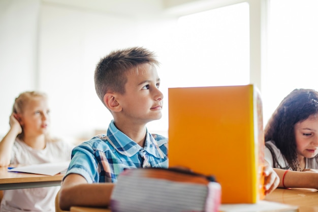 Niño, sentado, escuela, escritorio, tenencia, libro de texto