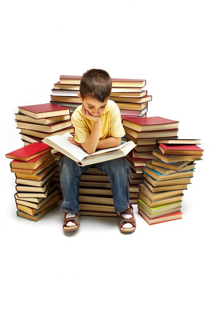 Niño sentado en una gran pila de libros