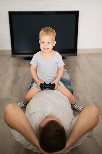 Niño sentado en el padre y jugando con joystick
